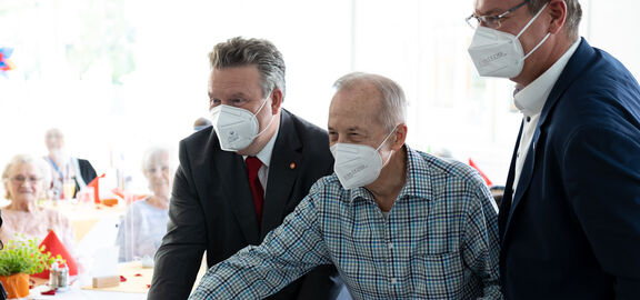 Bürgemerister Michael Ludwig (l.) und Bezirksvorsteher Georg Papai (r.) schnitten die Torte gemeinsam mit einem Tageszentrums-Kunden an.