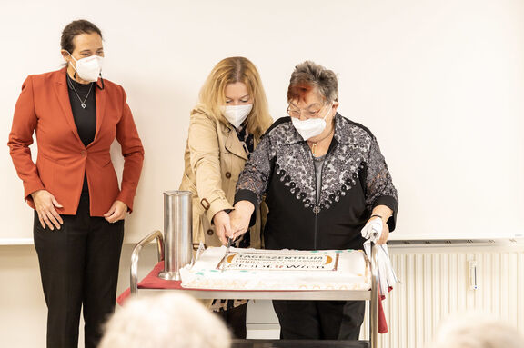 FSW-Geschäftsführerin Anita Bauer und die Geschäftsführerin der FSW-Tageszentren, Bianca Groß, beim Tortenanschnitt mit einer Kundin.
