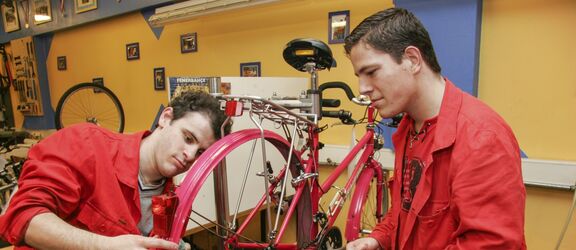 Zwei junge Burschen reparieren im Zuge der Berufsqualifizierung ein Fahrrad.
