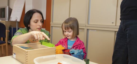 Frühförderin erklärt kleinem Mädchen die verschiedenen Bausteine