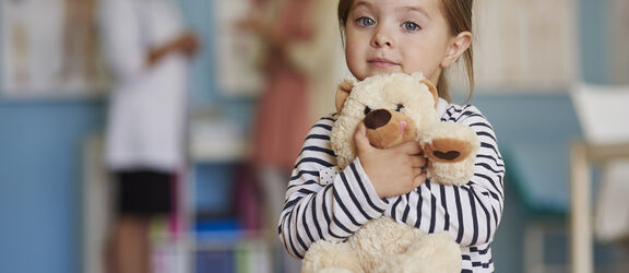 Kleines Mädchen umarmt einen Teddy-Bären