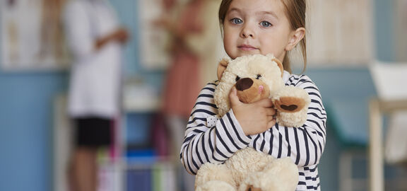 Kleines Mädchen umarmt einen Teddy-Bären