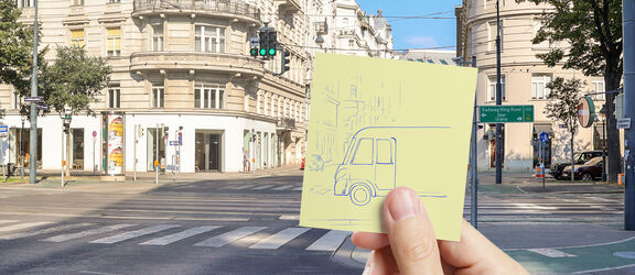 eine Hand hält ein Post-IT mit einem gezeichnetem Bus