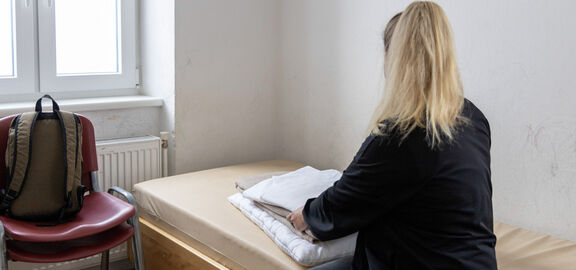 Frau sitzt auf einem Bett im Notquartier