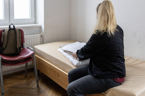 Frau sitzt auf einem Bett im Notquartier
