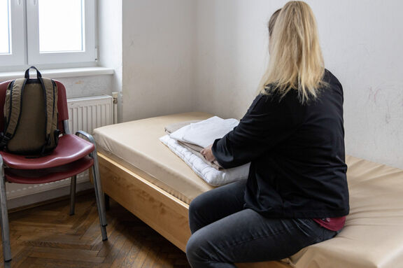 Frau sitzt auf einem Bett im Notquartier